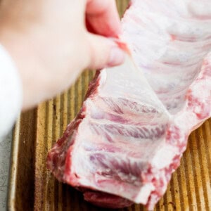 a person holding a piece of meat on a tray.