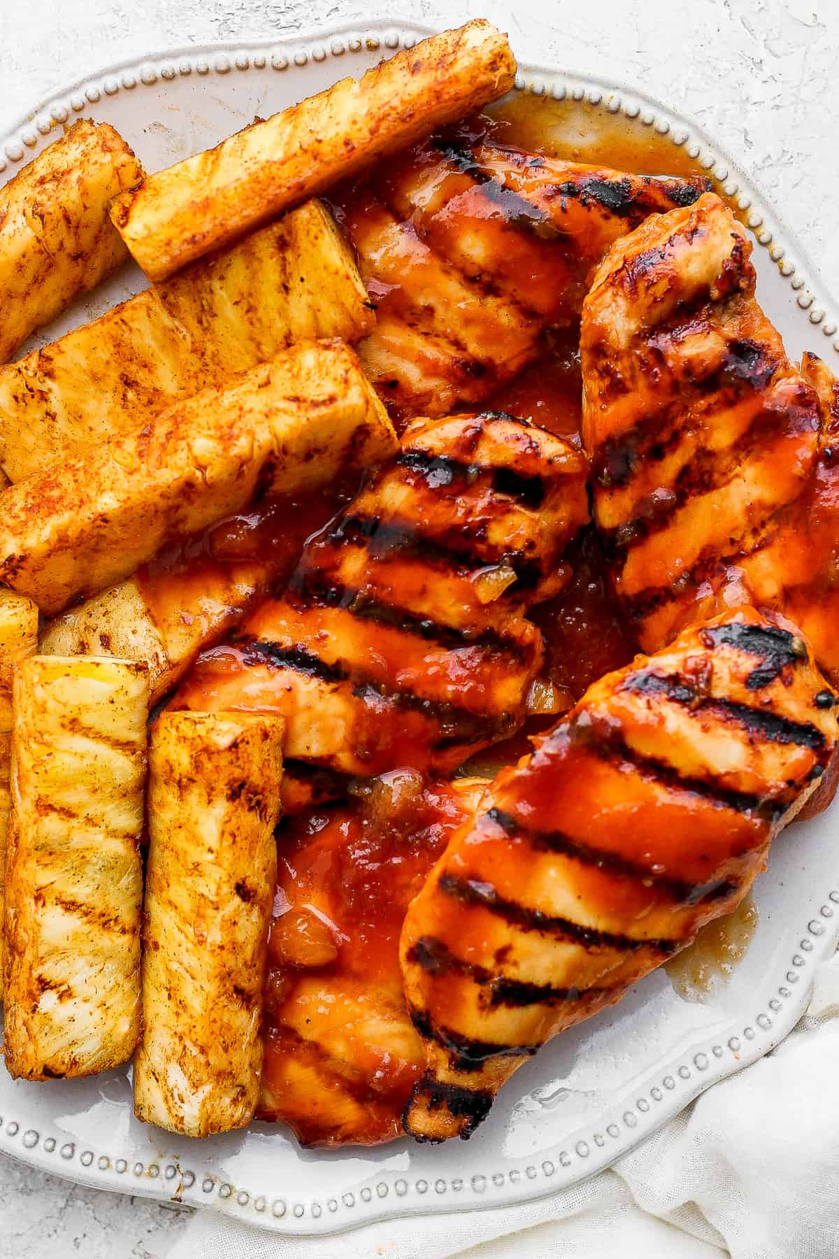 grilled chicken and pineapples on a white plate.