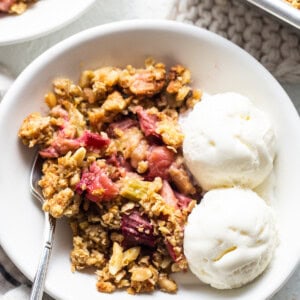 A bowl of cranberry crisp with ice cream and berries.