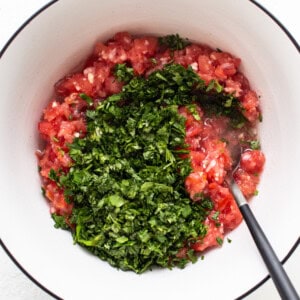 a bowl with tomatoes and herbs in it.