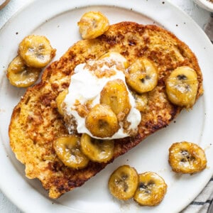 A plate of french toast with bananas and whipped cream.