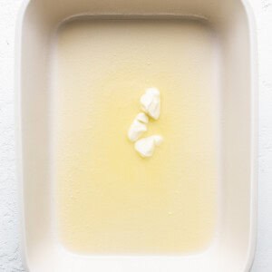 Butter in a baking dish on a white surface.