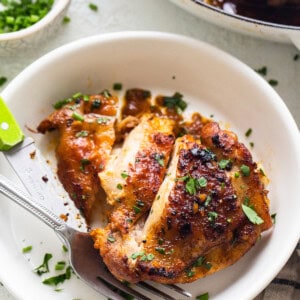 Chicken breast in a white plate with a fork.