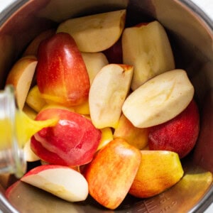 Sliced apples in a bowl with a liquid pouring over them.