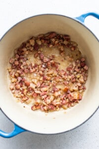 Bacon in a blue pot on a white surface.