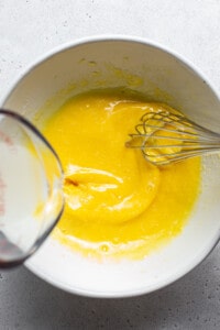 A bowl of yellow liquid with a whisk in it.