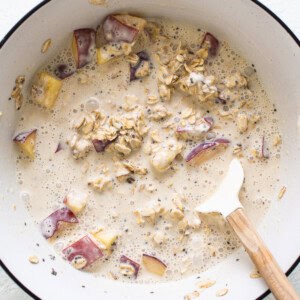 A bowl of oatmeal with apples and oats.