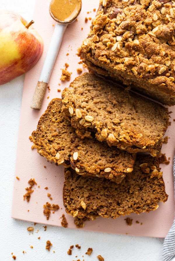 A slice of streusel bread with apples on a pink plate.