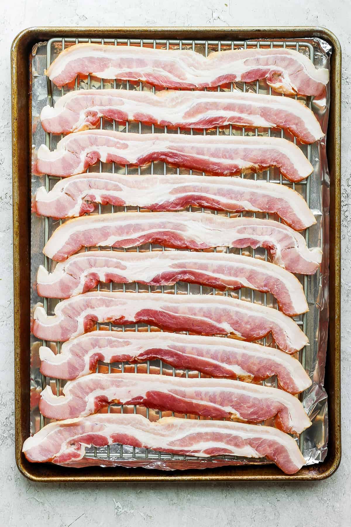 sliced bacon on a baking sheet.