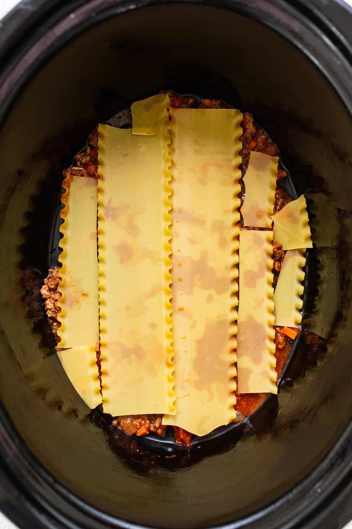 a crock pot filled with pasta and sauce.