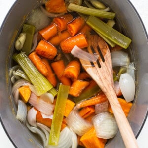 a pot filled with carrots, celery and onions.