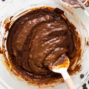 a bowl of chocolate pudding with a wooden spoon.