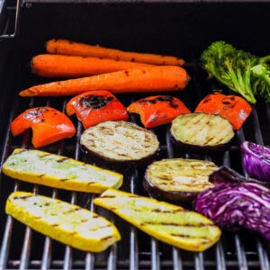 a bbq with carrots, broccoli, and other vegetables cooking on.