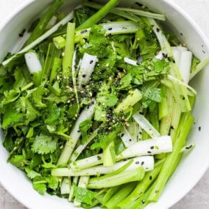 a bowl of greens with sesame seeds and sesame seeds.