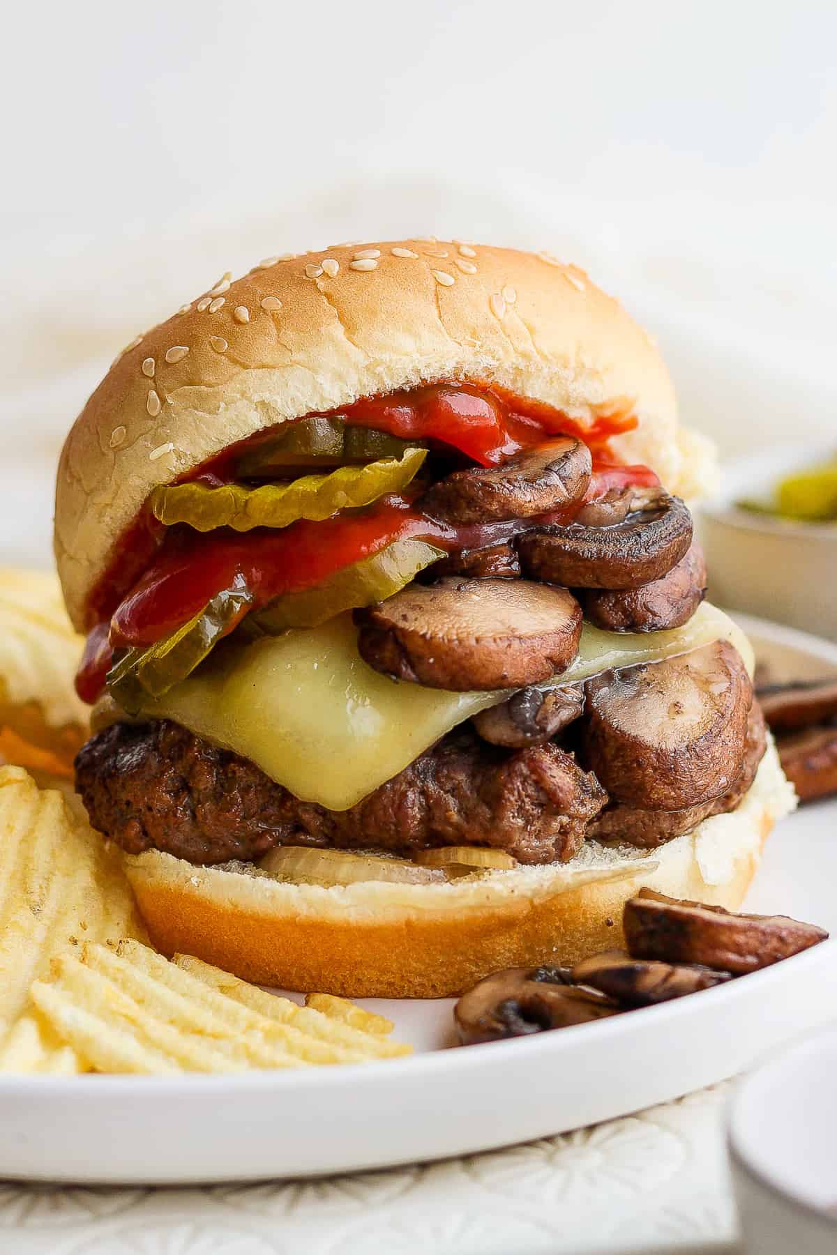 a burger with mushrooms and peppers on a plate.