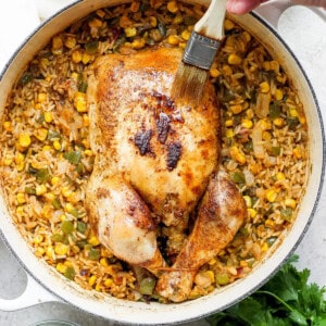 a person is slicing a chicken and rice in a skillet.