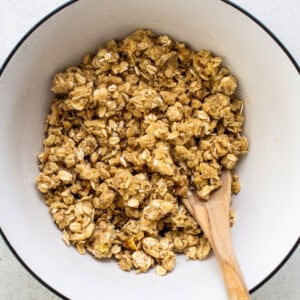 granola in a bowl with a wooden spoon.