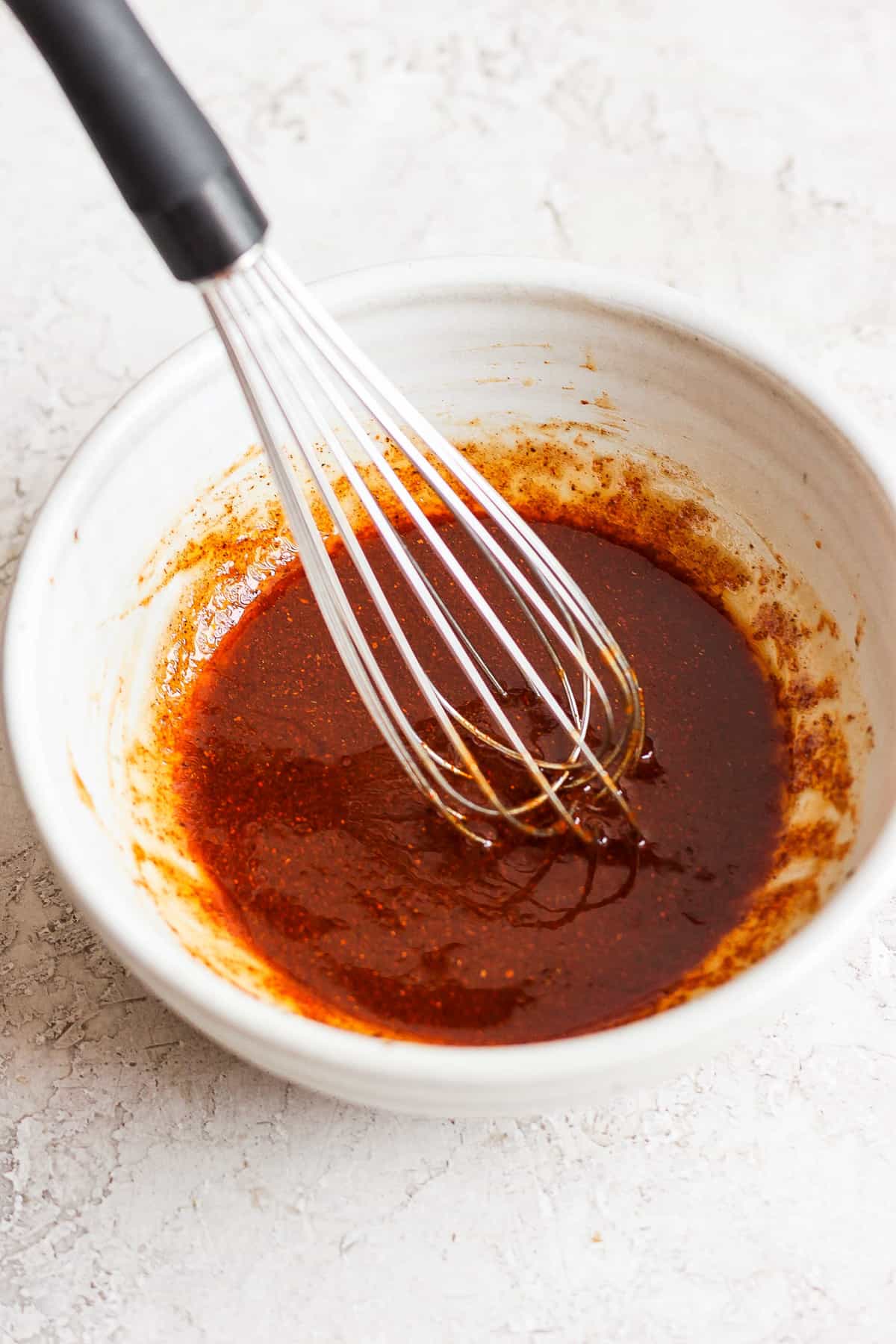 a bowl of sauce with a whisk in it.