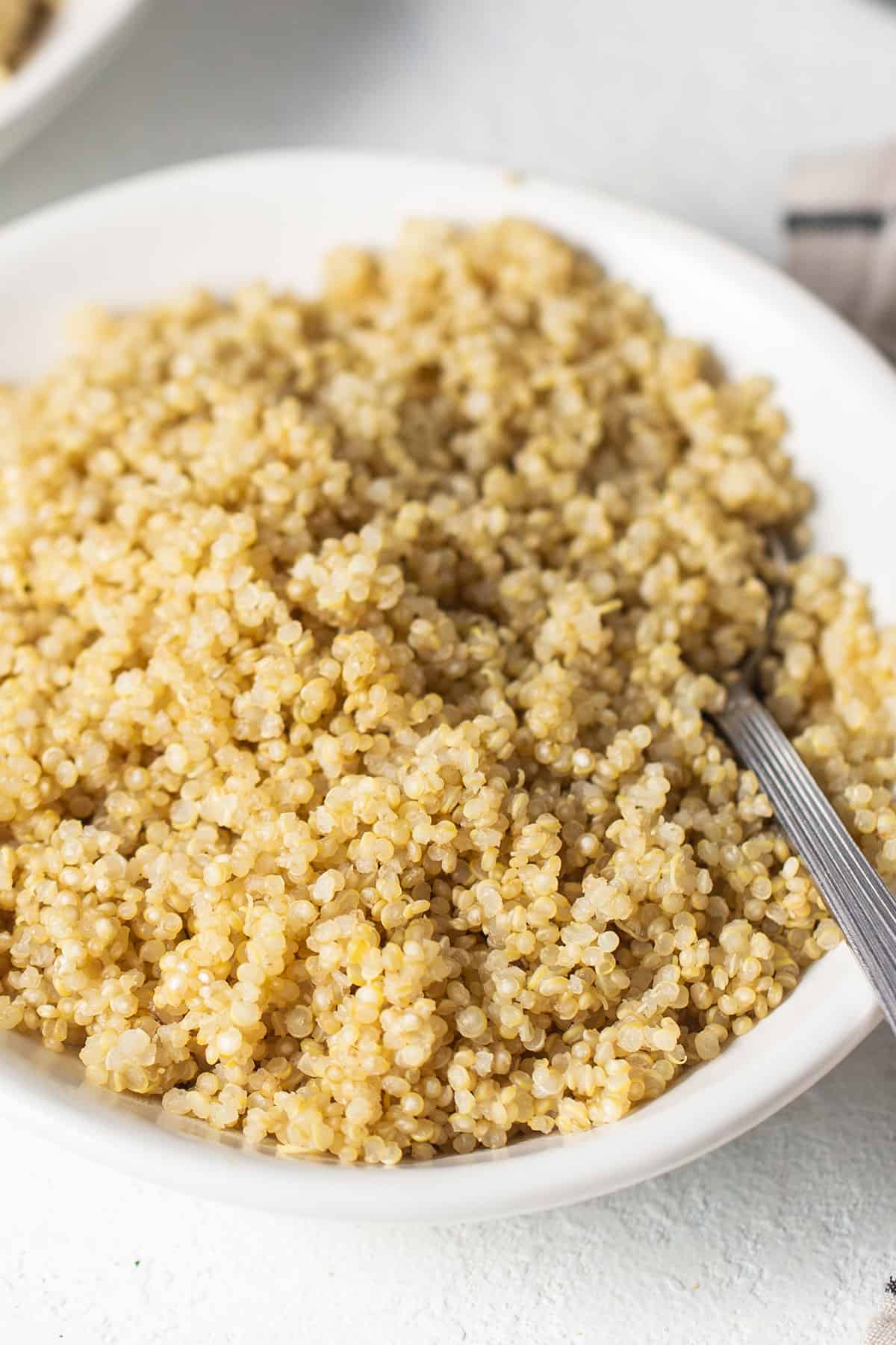 A white bowl filled with quinoa, cooked using the microwave method.