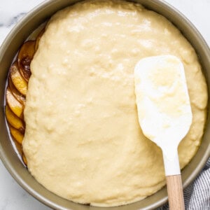 peach cake in a pan with a spatula.