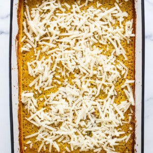 A white baking dish with a layer of cheese on top.