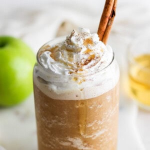 A mug with whipped cream and a cinnamon stick.