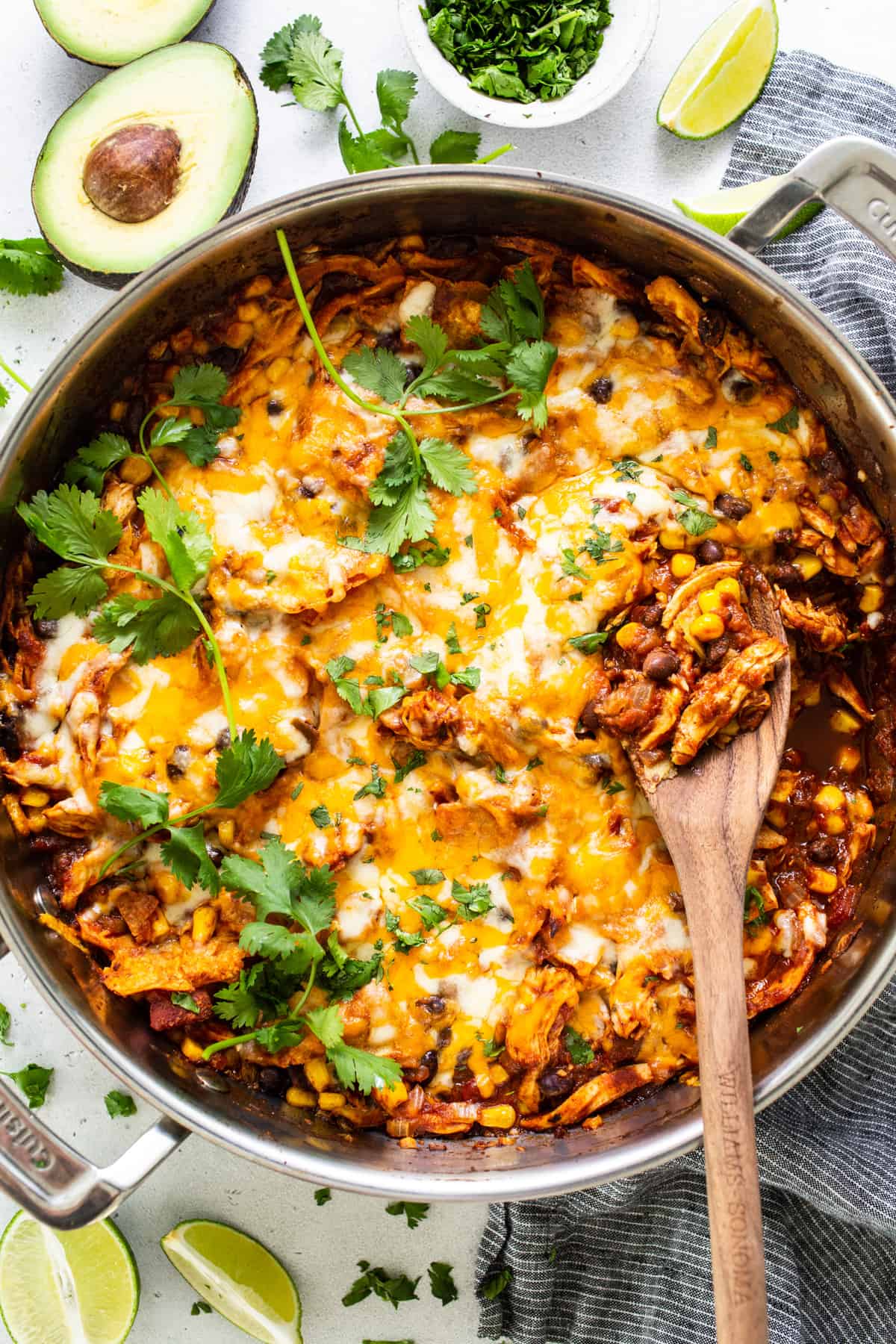 Mexican chicken enchilada in a pan with a wooden spoon.