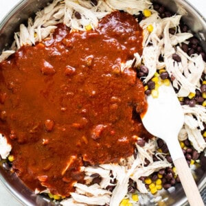 Mexican chicken in a skillet with sauce and corn.