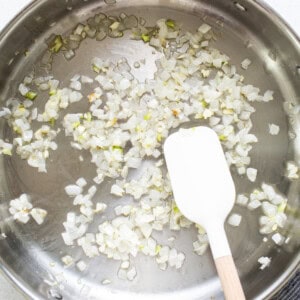 Sauteing onions in a pan with a wooden spatula.