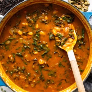 A pot full of soup with a spoon in it.