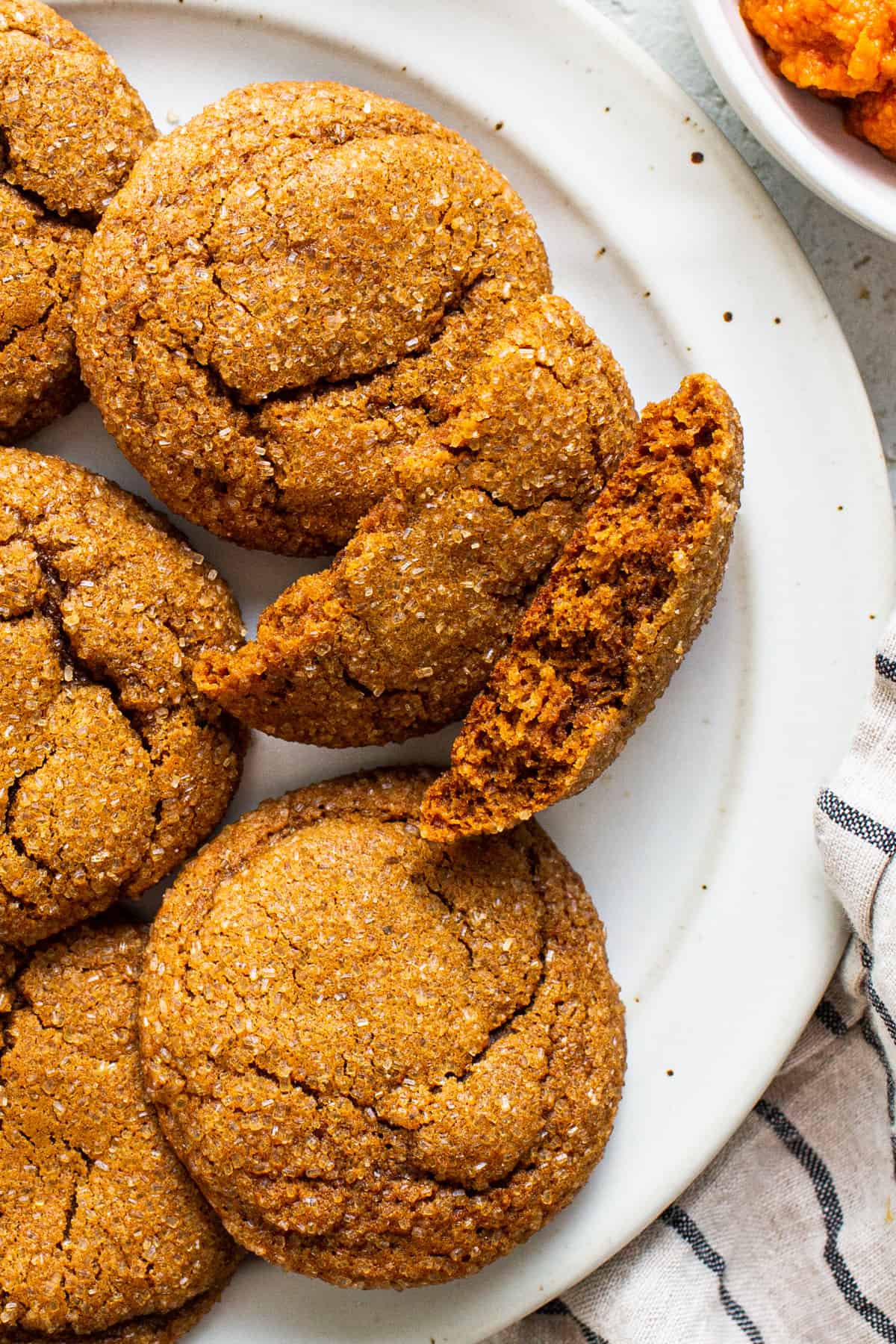 A plate of ginger cookies with a bite taken out of them.