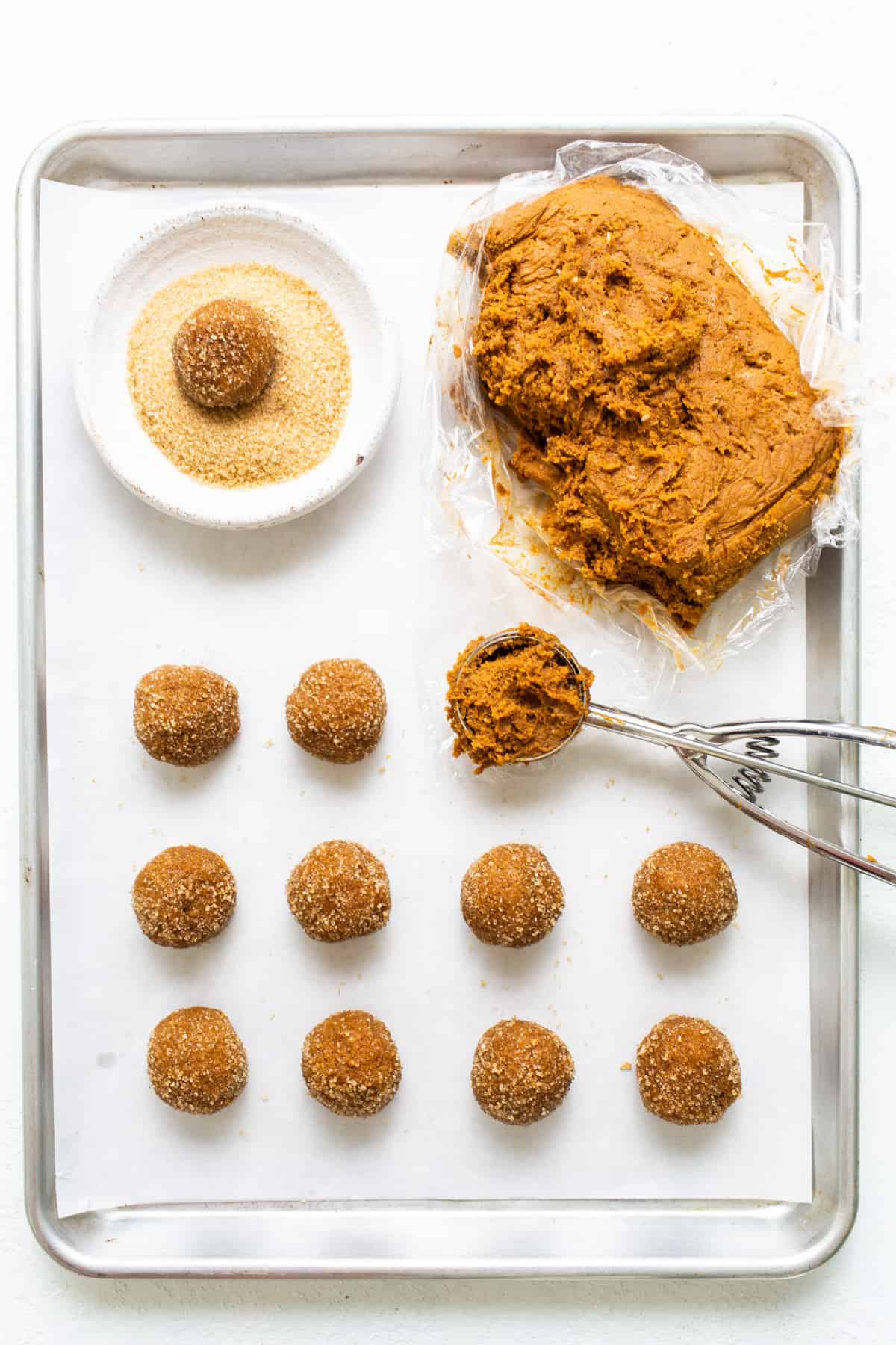 A baking sheet with a tray of doughnuts and a spatula.