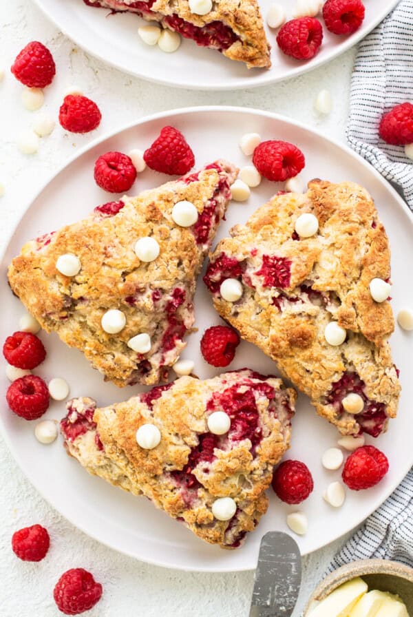 Raspberries and white chocolate scones on a white plate.