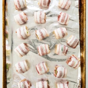 Bacon wrapped in foil on a baking sheet.