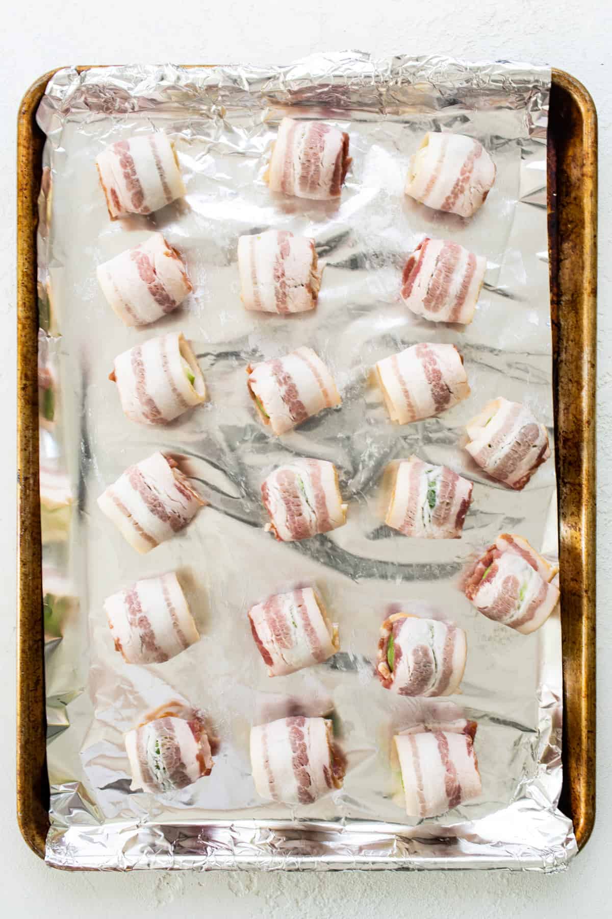 Bacon wrapped in foil on a baking sheet.