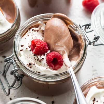 Chocolate mousse in jars with whipped cream and raspberries.