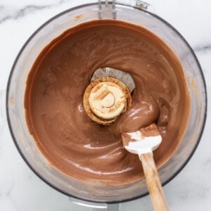 Chocolate ganache in a mixing bowl with a wooden spoon.