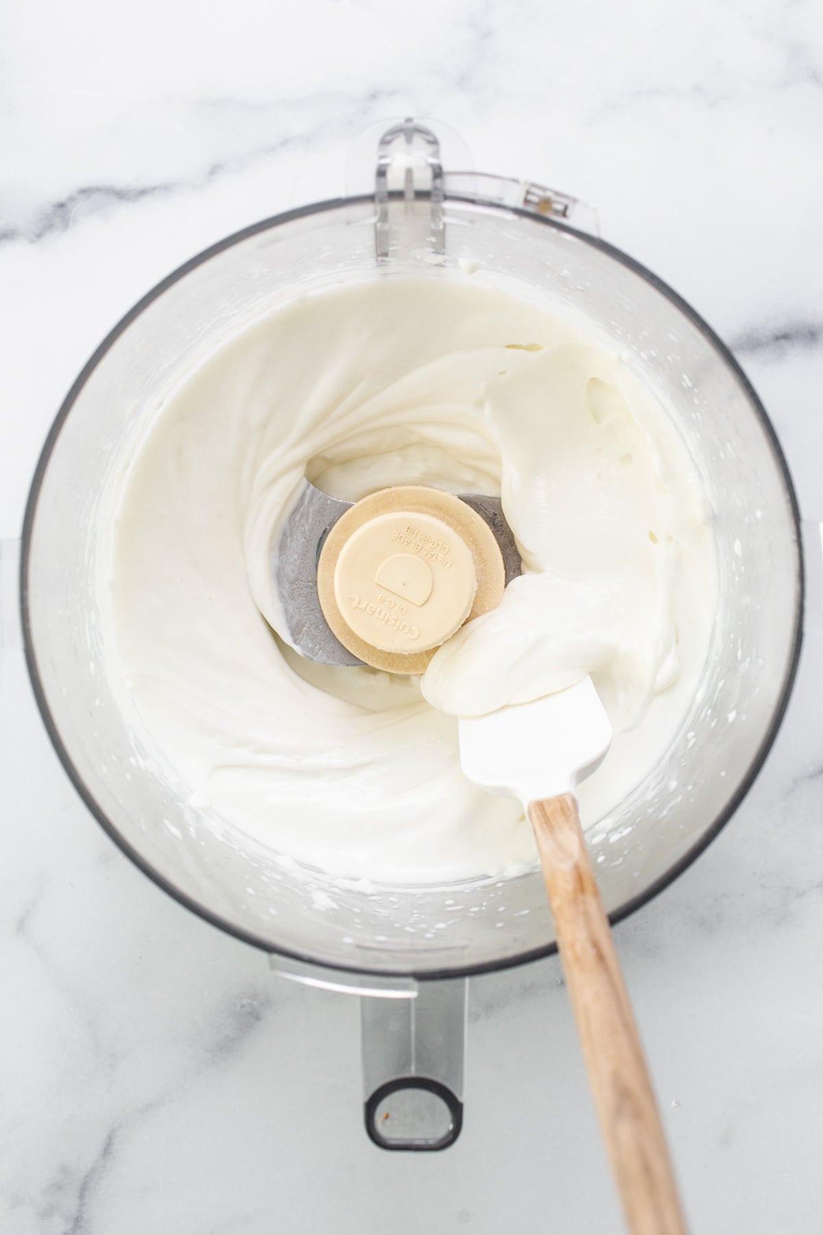 Whipped cream in a mixing bowl with a wooden spoon.