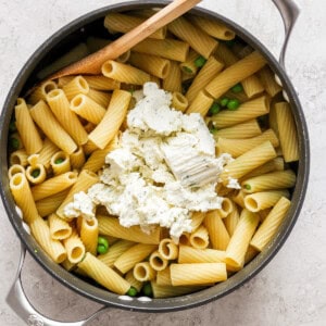 Penne pasta with peas and feta cheese in a skillet.