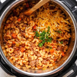 An instant pot full of macaroni and cheese with a wooden spoon.