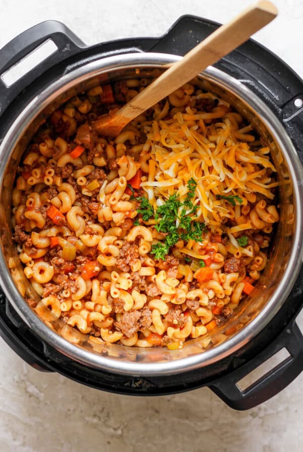 An instant pot full of macaroni and cheese with a wooden spoon.