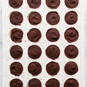 A tray of chocolate dipped cupcakes on a marble countertop.