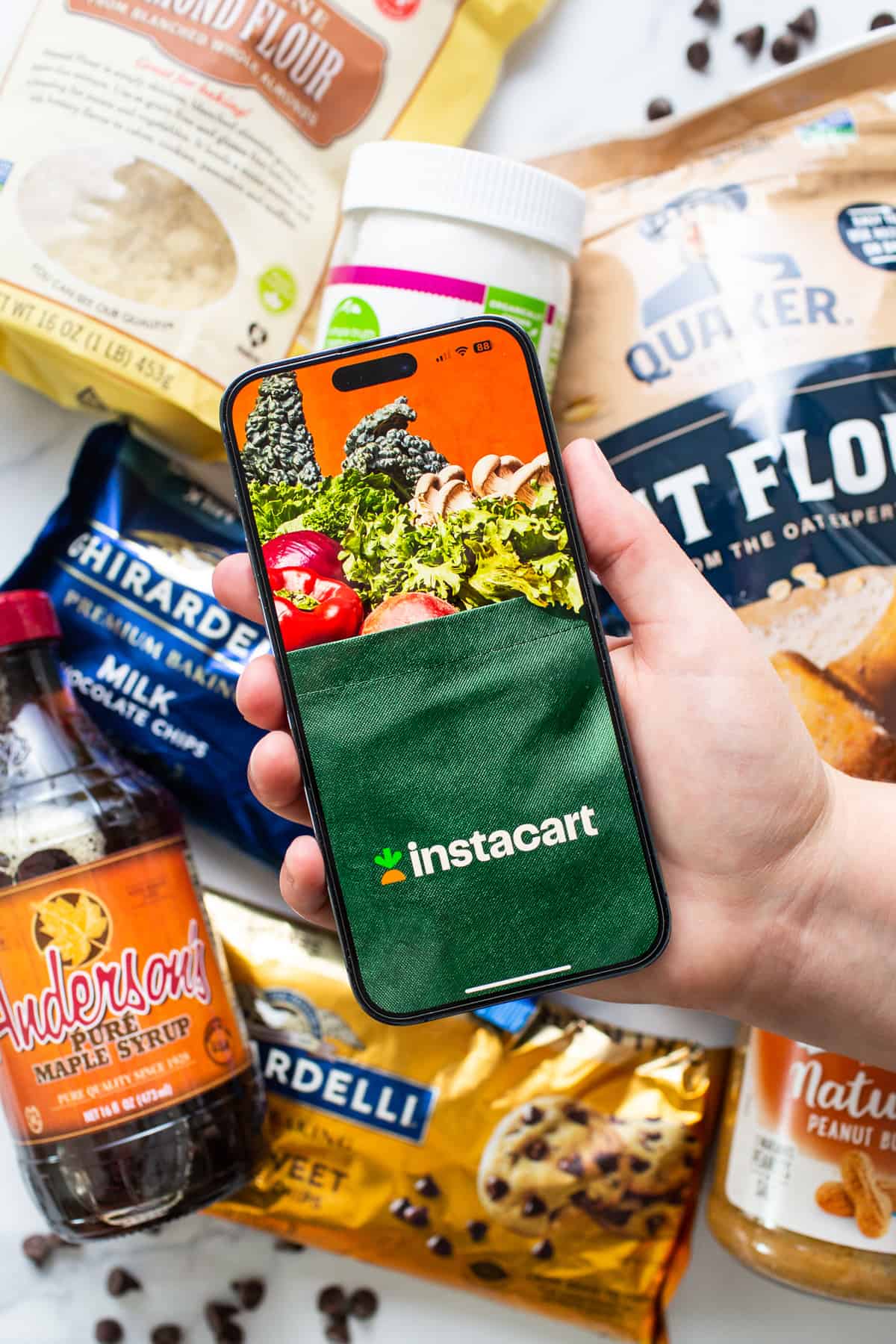 A person holding a phone next to a bag of food.