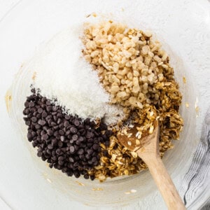 Granola and chocolate chips in a bowl with a wooden spoon.