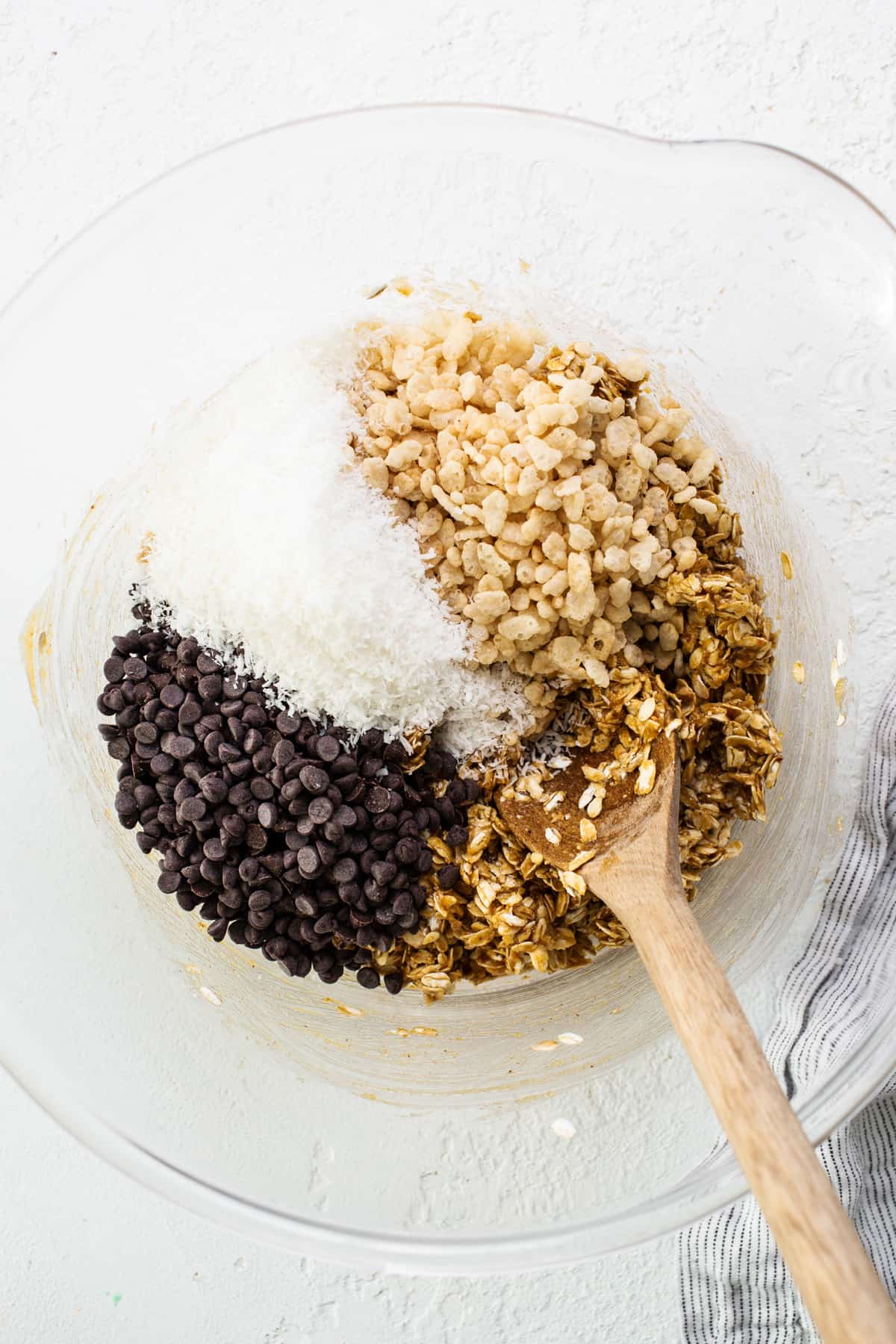 Granola and chocolate chips in a bowl with a wooden spoon.