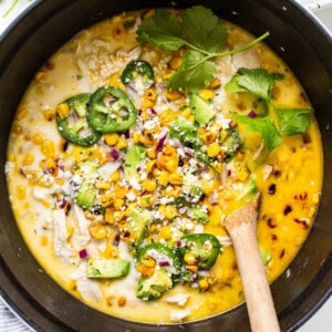 Chicken and corn soup in a pan with a wooden spoon.