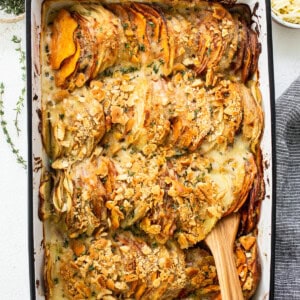 Sweet potato casserole in a baking dish with a wooden spoon.