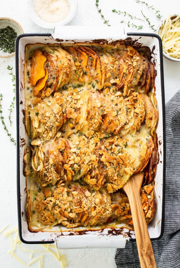 Sweet potato casserole in a baking dish with a wooden spoon.