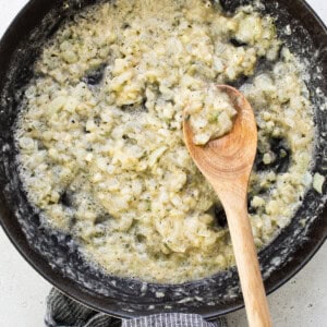 A frying pan with a wooden spoon in it.