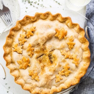 Apple pie on a plate with a glass of milk.